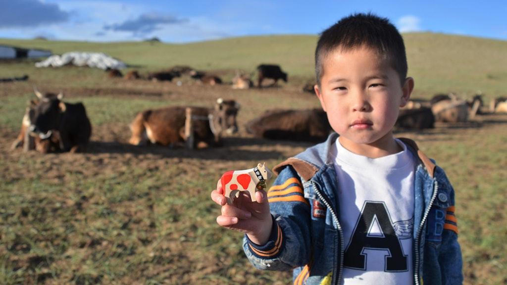Mongolian boy with wooden cow Happy Lilly